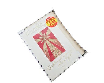 Puede incluir: Una tarjeta blanca con un diseño de estrella roja y dorada. La tarjeta tiene el texto "One perfect star to shine this Christmas" y "With love and best wishes for a shining Christmas night". Una pegatina roja y amarilla en la tarjeta dice "Now 50% off €7.49 €15.00".