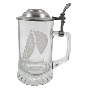 May include: Clear glass beer stein with a hinged metal lid and handle. The stein features an etched sailboat design with the number 12 and the text "ALTER RACING SLOOP RACED IN AMERICA'S CUP."