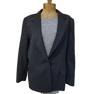 Op de afbeelding: Een zwarte blazer met een enkele knoopsluiting en een revers. De blazer heeft een klassieke, getailleerde pasvorm.