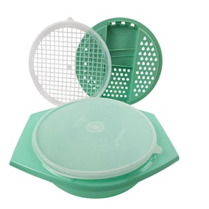 Puede incluir: Un recipiente de almacenamiento de alimentos verde claro con una tapa blanca y un inserto blanco en forma de rejilla. El recipiente tiene una base verde a juego y una segunda tapa verde con perforaciones. Sobre un fondo blanco.