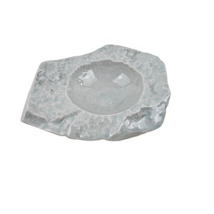 May include: A light blue ceramic bowl with a rough, textured exterior, resembling a rock. The bowl has a smooth, rounded interior.
