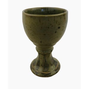May include: A green ceramic goblet with a textured surface and a wide base. The goblet is a traditional style with a round bowl and a tall stem.