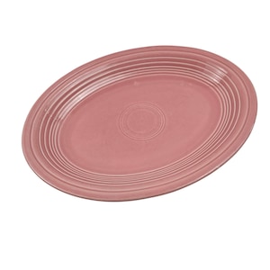 May include: A dusty rose oval serving platter with concentric ridged detailing. The ceramic dish has a smooth surface and a slightly raised center. This vintage-style platter is suitable for serving appetizers or entrees.