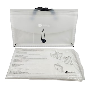 May include: Clear plastic expanding file folder with a black handle and closure. The folder has a curved flap and a black button closure. A package of DecoFile folders is below the file folder.