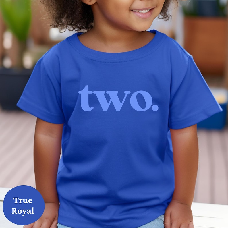 May include: A toddler wearing a royal blue t-shirt with the word "two" printed in light blue on the front.