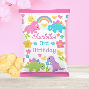 May include: A pink and white chip bag with a rainbow, sun, butterflies, and dinosaurs. The bag says "Charlotte's 3rd Birthday".