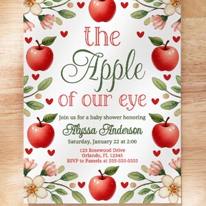 May include: A white baby shower invitation with a red apple and green leaves. The text reads "the Apple of our eye" and includes the name Alyssa Anderson, the date and time of the shower, and the address.
