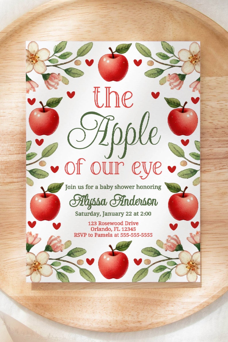 May include: A white baby shower invitation with a red apple and green leaves. The text reads "the Apple of our eye" and includes the name Alyssa Anderson, the date and time of the shower, and the address.