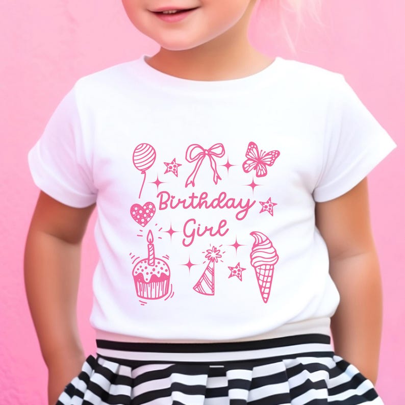 May include: White t-shirt with a pink graphic design that says "Birthday Girl" and features a cupcake, ice cream cone, butterfly, balloon, and stars.