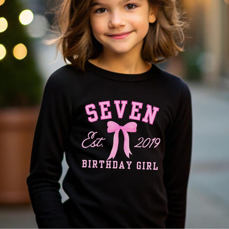 Peut inclure: T-shirt noir &agrave; manches longues avec l'inscription rose "SEVEN Est. 2019 BIRTHDAY GIRL" et un n&oelig;ud rose. V&ecirc;tement sur le th&egrave;me de l'anniversaire.