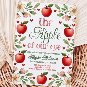 May include: A white baby shower invitation with a red apple and green leaves design. The text reads "the Apple of our eye" and includes the name Alyssa Anderson, the date and time of the shower, and the address.
