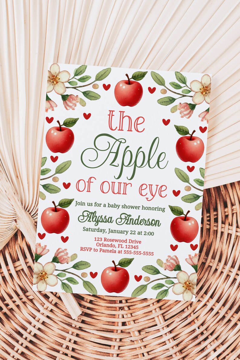 May include: A white baby shower invitation with a red apple and green leaves design. The text reads "the Apple of our eye" and includes the name Alyssa Anderson, the date and time of the shower, and the address.