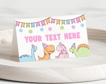 Puede incluir: Una tarjeta blanca con una pancarta rosa que dice "YOUR TEXT HERE". La tarjeta está decorada con dinosaurios coloridos que llevan sombreros de fiesta y una hilera de banderas de colores.