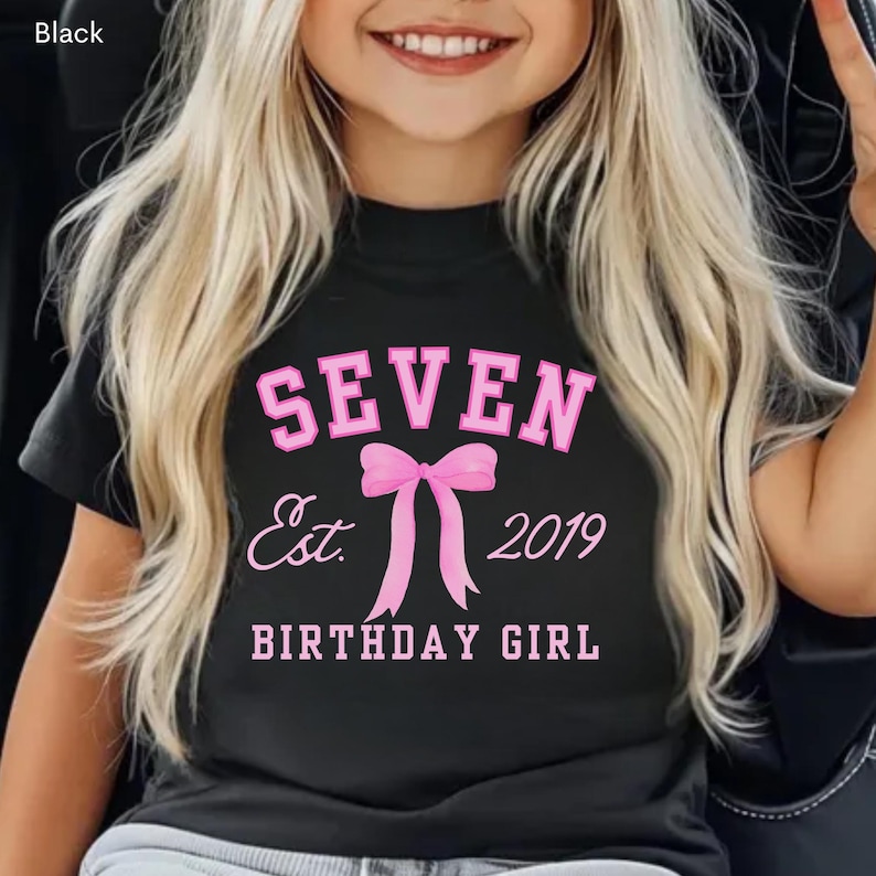 Peut inclure: T-shirt noir avec l'inscription rose "SEVEN Est. 2019 BIRTHDAY GIRL". Le motif comprend un n&oelig;ud rose. Il s'agit d'un v&ecirc;tement sur le th&egrave;me de l'anniversaire.