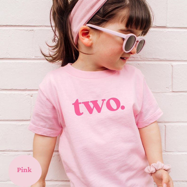 May include: Pink t-shirt with the word "two" in a pink font. The shirt is being worn by a child wearing a pink headband and sunglasses.