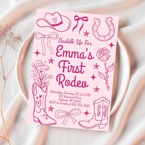 Puede incluir: Tarjeta de invitaci&oacute;n rosa con tem&aacute;tica de vaquero. La tarjeta presenta ilustraciones de un sombrero de vaquero, herradura, botas y una rosa. El texto dice "Saddle Up For Emma's First Rodeo". Incluye detalles del evento.