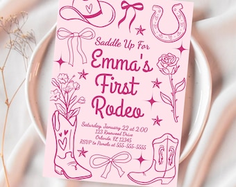 May include: Pink invitation card with a cowboy theme. The card features illustrations of a cowboy hat, horseshoe, boots, and a rose. Text reads "Saddle Up For Emma's First Rodeo". Includes event details.