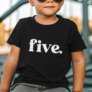 May include: Black t-shirt with a white pocket and the word "five." printed in a bold, sans-serif font. The shirt is short-sleeved and appears to be made of a soft material.
