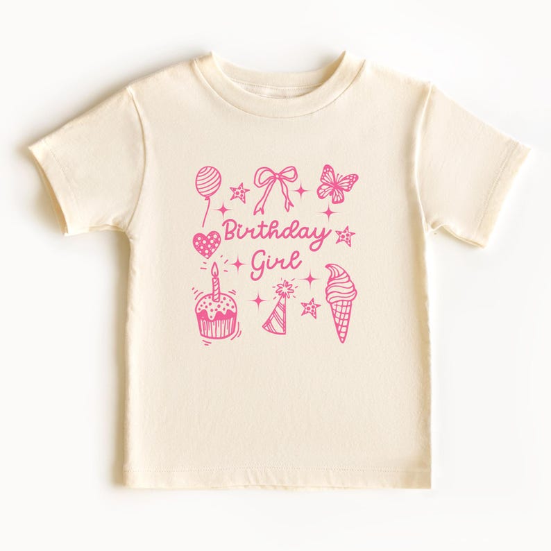 May include: A white t-shirt with a pink graphic design that says "Birthday Girl" and features a cupcake, ice cream cone, butterfly, balloon, and stars.
