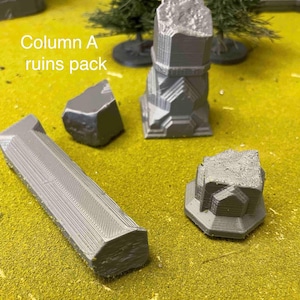 May include: A set of grey 3D printed ruins for tabletop gaming. The set includes a column, a broken pillar, a small rock, and a small block. The set is labelled "Column A ruins pack".