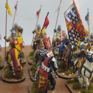 Könnte beinhalten: Eine Sammlung von handbemalten Miniatur-Metallfiguren, die mittelalterliche Ritter zu Pferd darstellen. Jeder Ritter trägt eine detaillierte Rüstung und führt ein einzigartiges heraldisches Schild oder Banner. Die Pferde sind farbig bemalt.