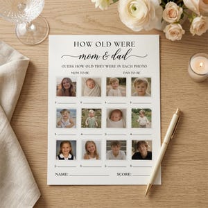 Może przedstawiać: Kremowa karta do gry na baby shower z napisem "HOW OLD WERE mom & dad". Karta ma miejsca na zdjęcia i odgadywanie wieku. Złoty długopis i zapalona świeca leżą na drewnianej powierzchni.