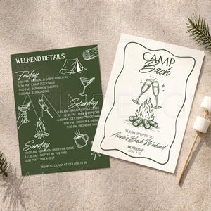 May include: Two invitation cards for a bachelorette weekend. One is dark green with white text and illustrations of camping activities. The other is off-white with a campfire and champagne glasses illustration. A sprig of pine and marshmallows on a stick are also present.