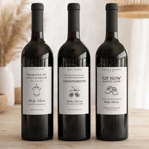 Pu&ograve; includere: Tre bottiglie di vino rosso con etichette personalizzate. Le etichette recitano "Promosso a Zio e Zia", "Nonni" e "Sip Now Babysit Later". Ogni etichetta include una grafica a tema bambino e il nome "Baby Olivia".