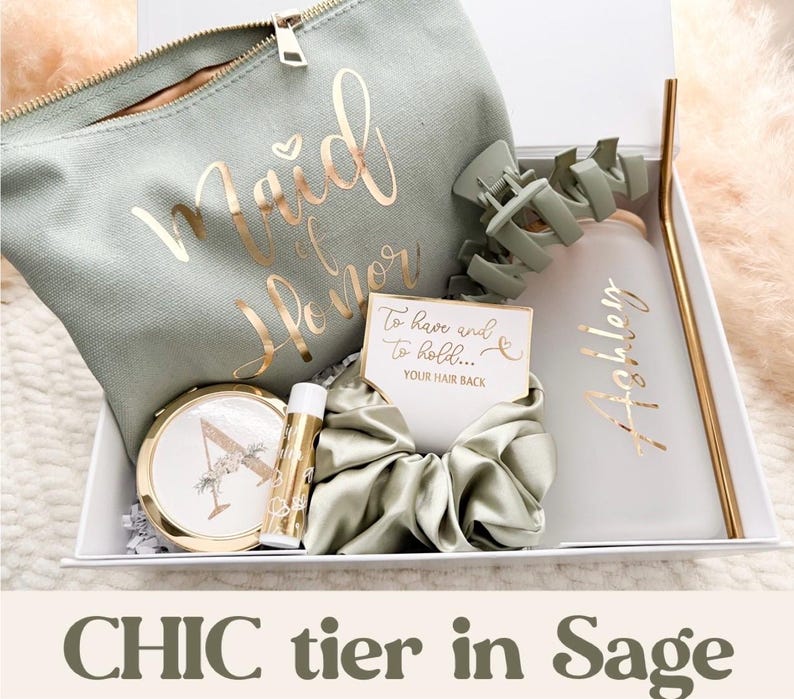 May include: A sage green gift box containing a makeup bag with gold script reading "Maid of Honor", a compact mirror, lip balm, a scrunchie, a water bottle with a gold straw, and a card. The text "CHIC tier in Sage" is at the bottom.