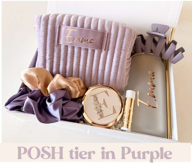 Peut inclure: Coffret cadeau violet comprenant une pochette en velours c&ocirc;tel&eacute; lavande avec le nom "Emma", un miroir de poche, un baume &agrave; l&egrave;vres, une pince &agrave; cheveux, une bouteille d'eau et des chouchous. Le texte "POSH tier in Purple" est en bas.