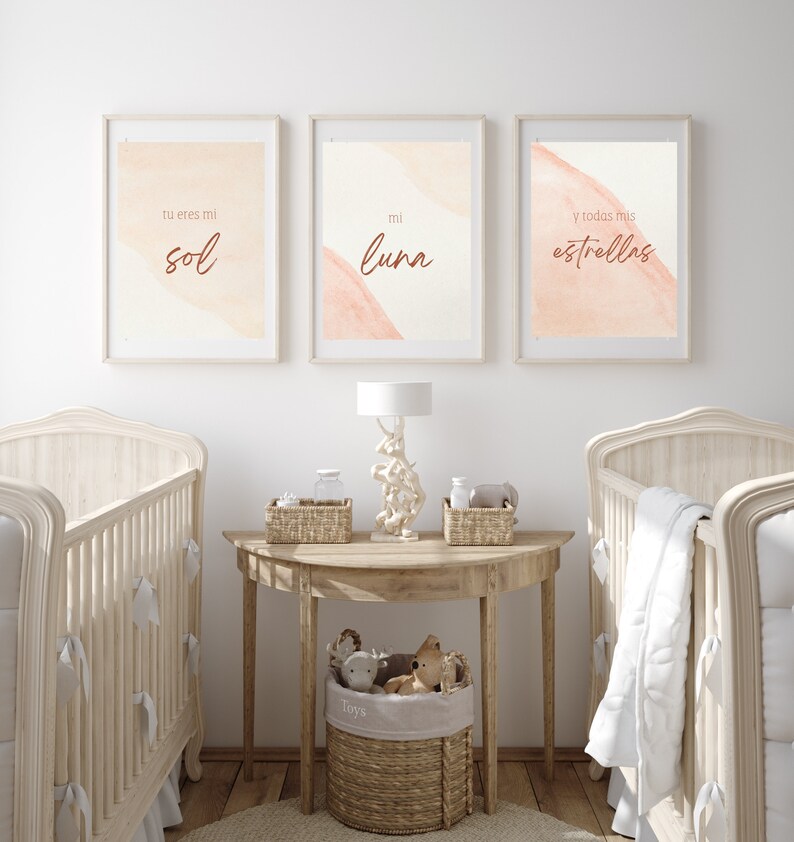 May include: Three framed prints with watercolor-style backgrounds in shades of peach and cream. The prints feature Spanish text that reads "tu eres mi sol", "mi luna", and "y todas mis estrellas". The prints are displayed above a wooden table with a lamp and baskets.