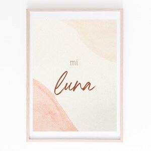 May include: A framed print with a watercolor background in shades of peach and cream. The text "mi luna" is written in brown cursive script.