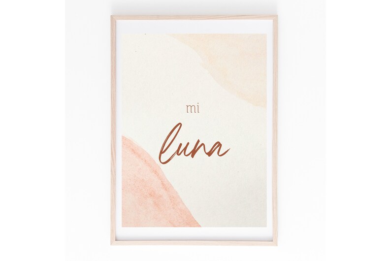May include: A framed print with a watercolor background in shades of peach and cream. The text "mi luna" is written in brown cursive script.
