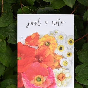 May include: A white card with the text "just a note" written in black cursive. The card features a watercolor illustration of a bouquet of red, orange, and yellow poppies and white daisies.