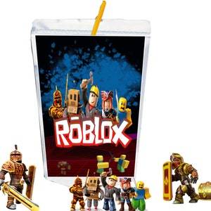 May include: A juice box featuring the Roblox logo and characters, with a yellow straw. Several Roblox character figurines are positioned around the juice box. The background of the juice box is dark blue with white accents.