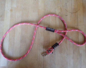 May include: A red and purple rope dog leash with two black leather handles and a silver metal clip.