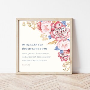 Könnte beinhalten: Ein druckbares Wandbild mit einem Aquarell-Blumenarrangement mit rosa und blauen Blumen. Der Text lautet "Der Mensch ist wie ein Baum, der an Wasserbächen gepflanzt ist. der seine Früchte zur rechten Zeit trägt und dessen Blätter nicht welken, was er auch tut, er gedeiht. Psalm 1.3"