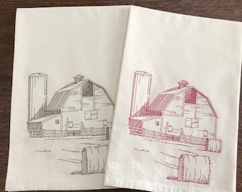 May include: Two white kitchen towels with a brown and red embroidered design of a farmhouse with a silo and hay bales.
