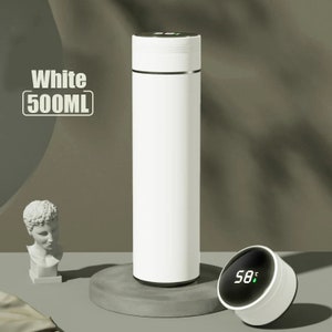 A white cylindrical thermos with a digital temperature display showing 33°C on its lid, placed on a white surface.