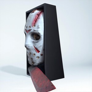 May include: A white hockey mask with red accents and a blood-stained gash, emerging from a black box. A blood-red, rectangular blade extends from the box, suggesting a horror theme.
