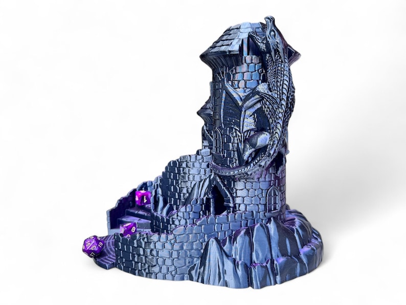 May include: A 3D printed dice tower shaped like a stone tower with a dragon wrapped around it. The tower has a purple iridescent finish and is designed to hold dice for tabletop games.