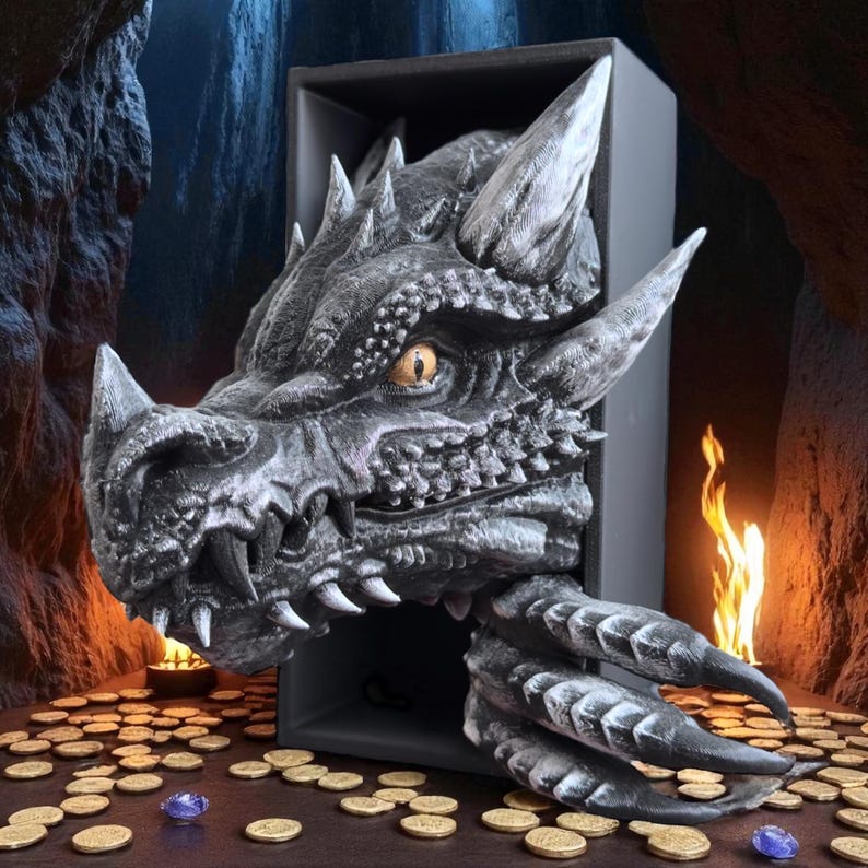 May include: A detailed, gray dragon sculpture with sharp horns, teeth, and claws emerges from a dark box. The dragon's eye is a striking yellow. Gold coins and a blue gem are scattered around the base, with a small flame in the background.