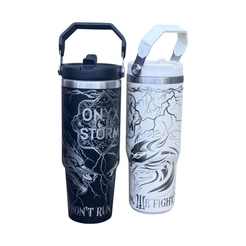 May include: Two stainless steel insulated tumblers with handles. One is black with a wolf design and the text "ONYX STORM" and "DON'T RUN". The other is white with a similar design and the text "WE FIGHT".