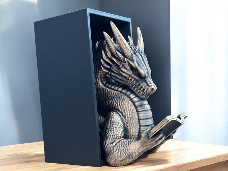 May include: A gold dragon bookend with a black base, holding a book in its claws. The dragon is detailed with scales and has a fierce expression.