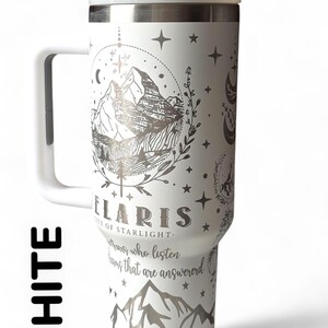 Puede incluir: Taza de viaje blanca con asa y tapa. La taza presenta un dise&ntilde;o de monta&ntilde;a y celestial en plata, con la palabra "Polaris" y la frase "City of Starlight" impresas en la parte delantera. La taza tambi&eacute;n tiene el texto "Aquellos que escuchan, sue&ntilde;os que son respondidos".