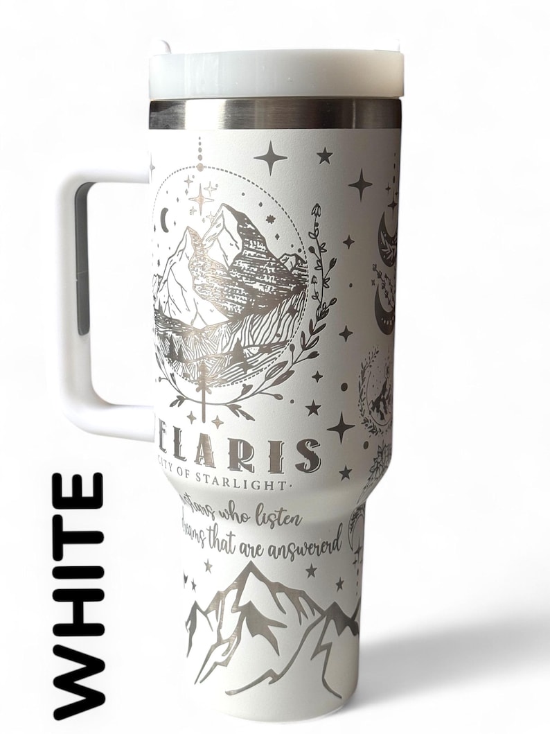 Puede incluir: Taza de viaje blanca con asa y tapa. La taza presenta un dise&ntilde;o de monta&ntilde;a y celestial en plata, con la palabra "Polaris" y la frase "City of Starlight" impresas en la parte delantera. La taza tambi&eacute;n tiene el texto "Aquellos que escuchan, sue&ntilde;os que son respondidos".