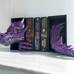 A purple dragon bookend elegantly supports a book, adding a whimsical touch to the bookshelf decor.
