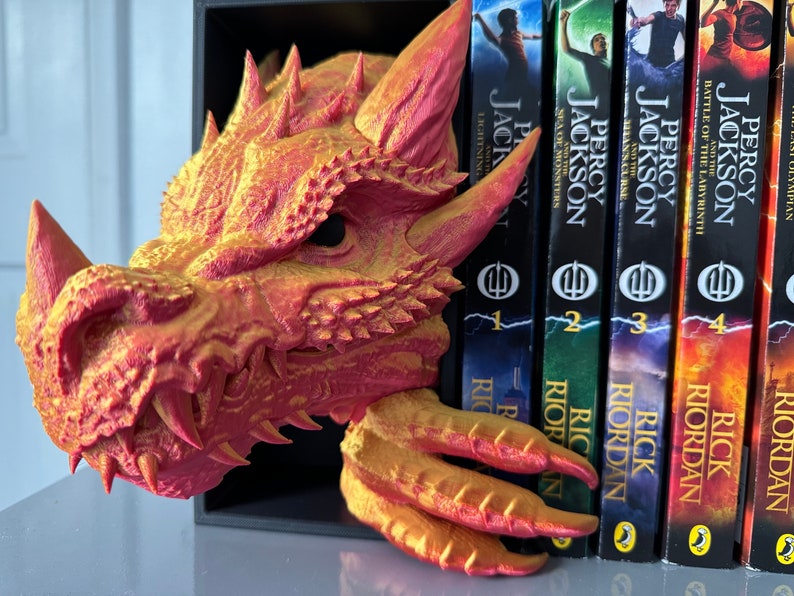 A decorative dragon bookend holding multiple books, adding a whimsical touch to a bookshelf filled with literary treasures.