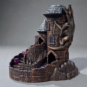 May include: A brown and gray castle-shaped dice tower with a dragon sculpture on the side. The tower has a stone brick design, arched windows, and a sloped roof. Purple dice are visible on the steps and inside the tower.