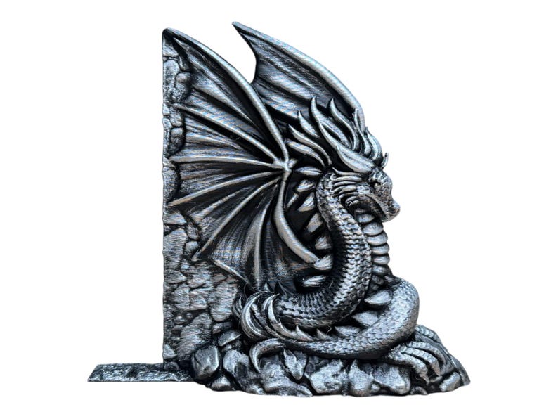 May include: A silver dragon bookend with wings spread wide and a textured stone base. The dragon is curled up with its head resting on its tail.